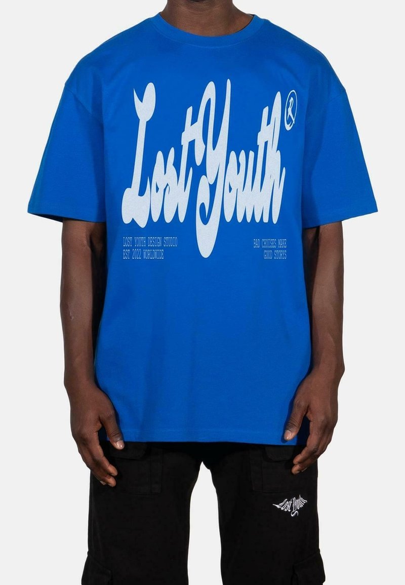 Sininen puuvillapaita lyhyillä hihoilla, jossa on rohkeaa valkoista tekstiä "Kadonnut nuoruus." Rentomallinen, pyöreä pääntie, yksinkertainen muotoilu, ei kuvioita.