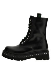 Bottes de cheville en cuir noir avec des lacets verts, �œillets en argent et plateforme cloutée. Comprend une languette de traction et une semelle texturée.
