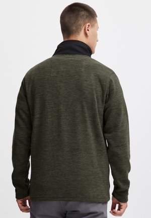 Grüner Fleece-Pullover mit schwarzem Kragen, ausgestattet mit einem strukturierten Stoff und langen Ärmeln. Die Rückansicht zeigt ein einfaches Design ohne Verzierungen.