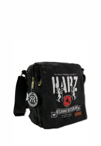 Black canvas messenger bag featuring a frontal graphic design with "HARZ", animal silhouettes, and patches; has a zippered closure and adjustable strap.