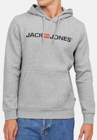 Grå hoodie med kængurulomme, snoretræk og sort "JACK & JONES" logo. Lavet af blødt, tekstureret stof. Ribbet manchetter og kant.