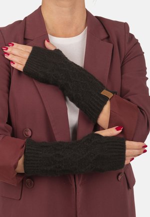 Persoon draagt zwarte, gebreide handschoenen zonder vingers met een ruitpatroon en een bordeauxrode blazer, armen gekruist over de borst.