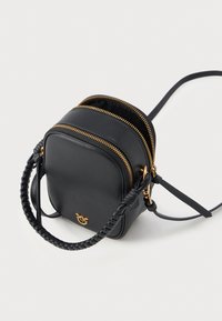 Melnas ādas crossbody soma ar gludu apdari, diviem rāvējslēdzēju nodalījumiem, zelta tonī apdari un pītām rokturim.