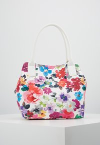 Květinová taška přes rameno s bílým pozadím, zdobená živými květinami v růžové, červené, modré a fialové barvě. Má bílé uši a strukturovaný tvar.