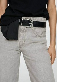 Ljust grå denimbyxor med en avslappnad passform, detaljerade fickor och ett svart läderbälte med en silverspänne, bära med en svart topp.