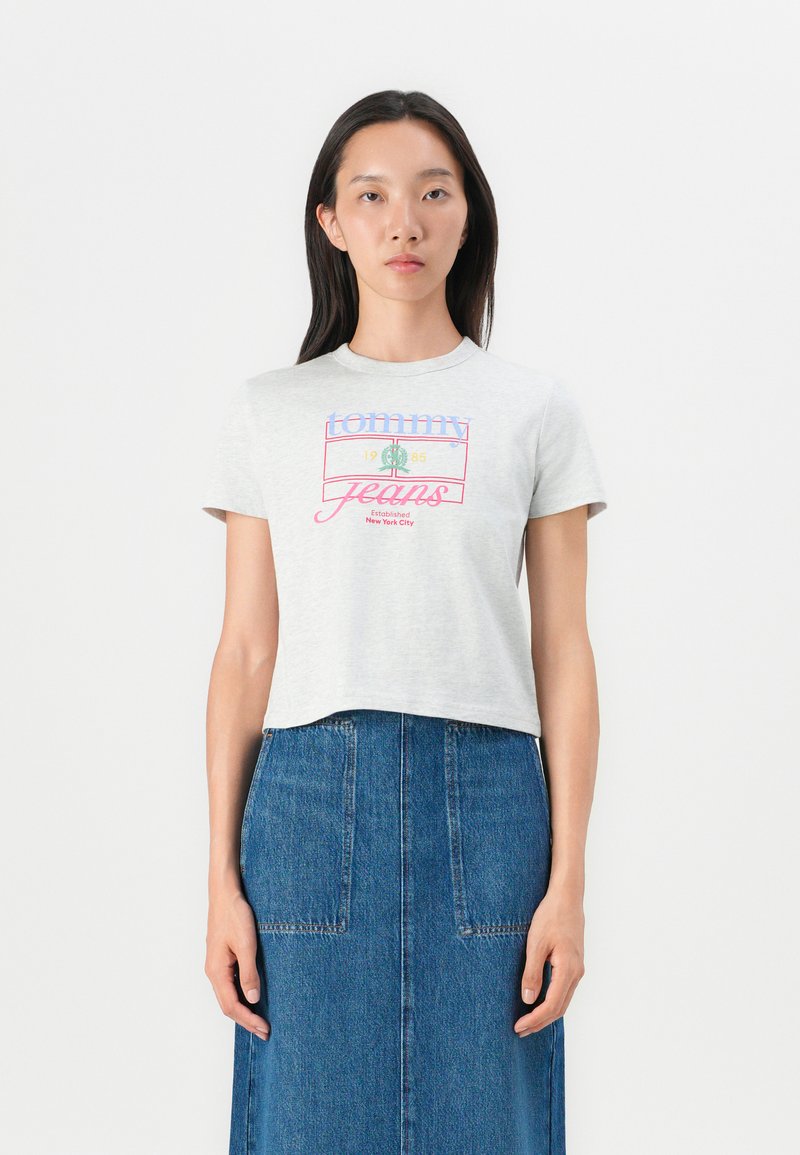 Šedé skrátené tričko s krátkymi rukávmi, s multicolor textom "tommy jeans" a logom. Skombinované s modrou džínovou sukňou.