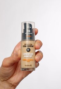 Beżowa butelka podkładu z pompką, oznaczona "Revlon Colorstay Longwear Makeup", SPF 15. Zawiera witaminę E, dla skóry mieszanej/tłustej, 30 mL.