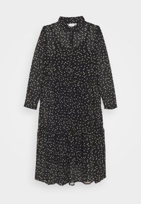 Svart långärmad klänning i genomskinligt tyg med lager på lager-skjort. Har en krage och små beige hjärtformade mönster överallt.