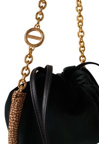 Velvet green bag with a black leather strap and gold chain. Features a textured brown accent and a round gold hardware detail.