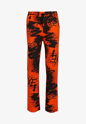 Los pantalones deportivos naranjas presentan un patrón negro de estilo graffiti, diseñados con una cintura elástica y cordón para un ajuste ajustable.