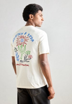 Crèmefarbiges Baumwoll-T-Shirt mit einem bunten Blumen-Graphic auf der Rückseite, mit dem Schriftzug "Scotch & Soda" und "Amsterdam 1985".