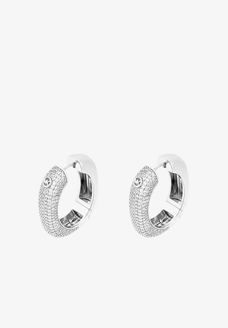 Boucles d'oreilles en argent en forme de créoles avec une surface texturée, incrustées de pierres transparentes étincelantes. Le design comprend un petit accent logo.