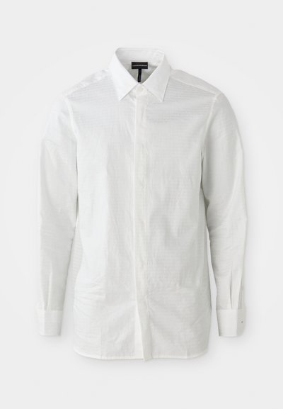 Balts garām piedurknēm krekls, kas izgatavots no viegla auduma ar strukturētu apkakli, priekšējo pogu slēgšanu un smalku tekstūras rakstu uz auduma.