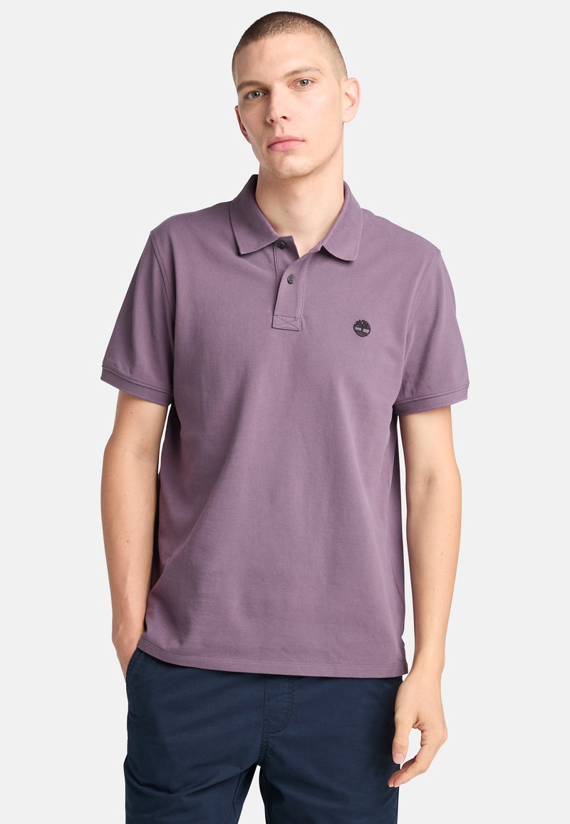 Fialová bavlněná polo tričko s límečkem, krátkými rukávy a malým černým logem na hrudi. Jemně texturovaná látka a klasický střih.