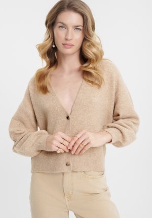 Cardigan tricoté en beige clair, avec un décolleté en V profond, fermeture à boutons et manches volumineuses. Tissu texturé avec des poignets et un ourlet côtelés.
