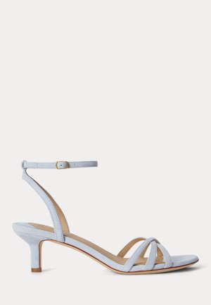 Sandale à talon kitten en daim bleu clair avec bride à la cheville et boucle, bout ouvert, et brides croisées à l'avant.