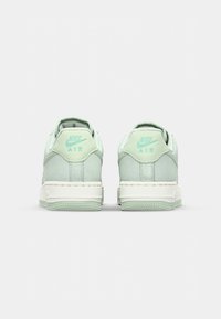 Sneakers Nike Air z górną częścią wykonaną z jasnej zielonej zamszowej tkaniny, wyściełanym kołnierzem, białą podeszwą i wytłoczonym logo na akcentach pięty.