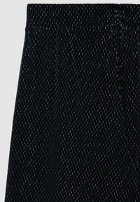 Tessuto nero testurizzato con un motivo intrecciato e una finitura morbida. Vita elastica nella parte superiore, adatta per un abbigliamento casual o rilassato.
