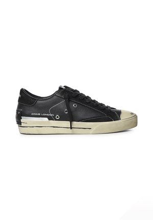Scarpa da ginnastica nera bassa con suola bianca, lacci neri, occhielli in metallo e testo "Crime London" sul lato.