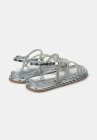 Zilveren sandalen met platte zolen, voorzien van metallic banden en een gestructureerd ontwerp. Verstelbare enkelband met een vierkante gespsysteem.