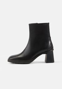 Bota de cuero negro hasta el tobillo con punta cuadrada y tacón cuadrado. Textura suave y diseño limpio, con un mínimo de adornos.