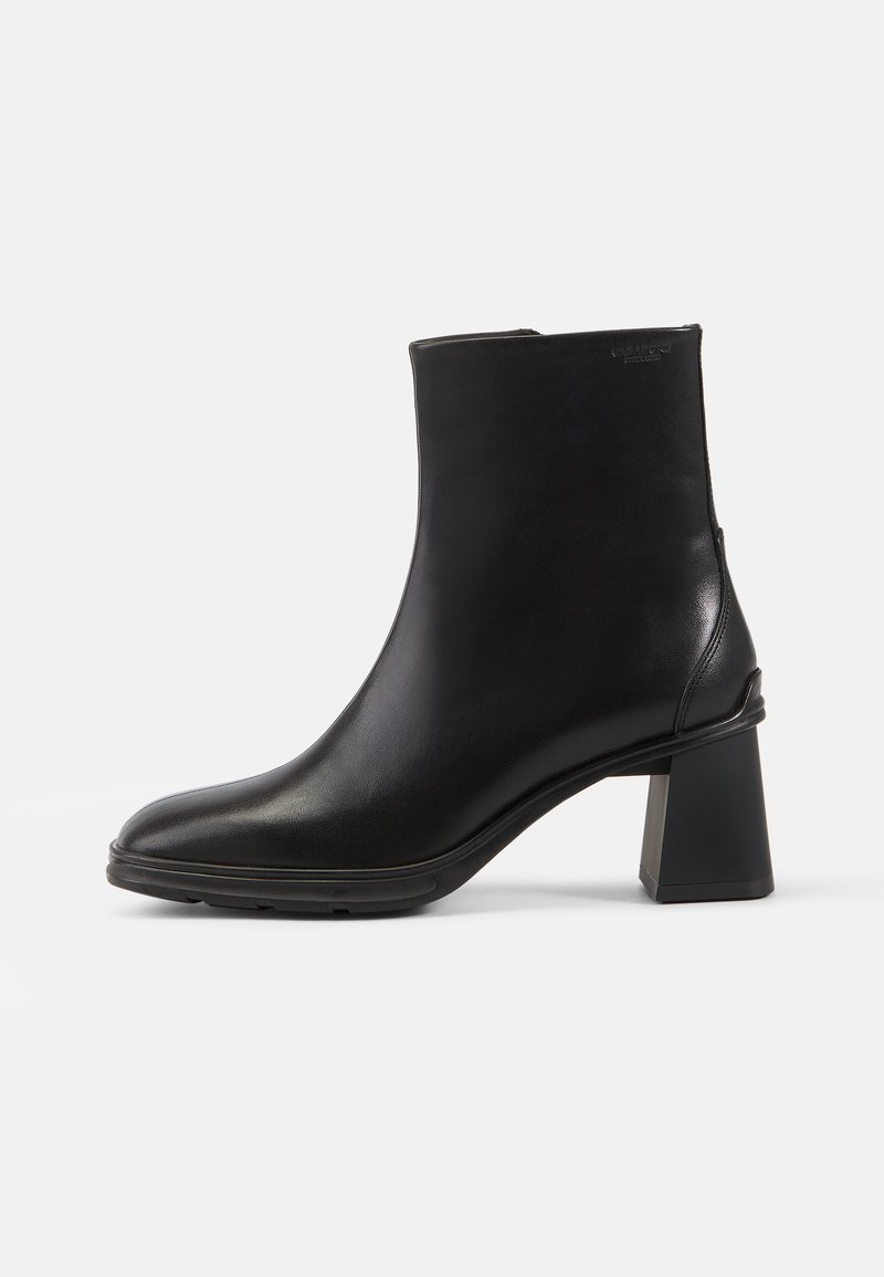 Bota de cuero negro hasta el tobillo con punta cuadrada y tacón cuadrado. Textura suave y diseño limpio, con un mínimo de adornos.