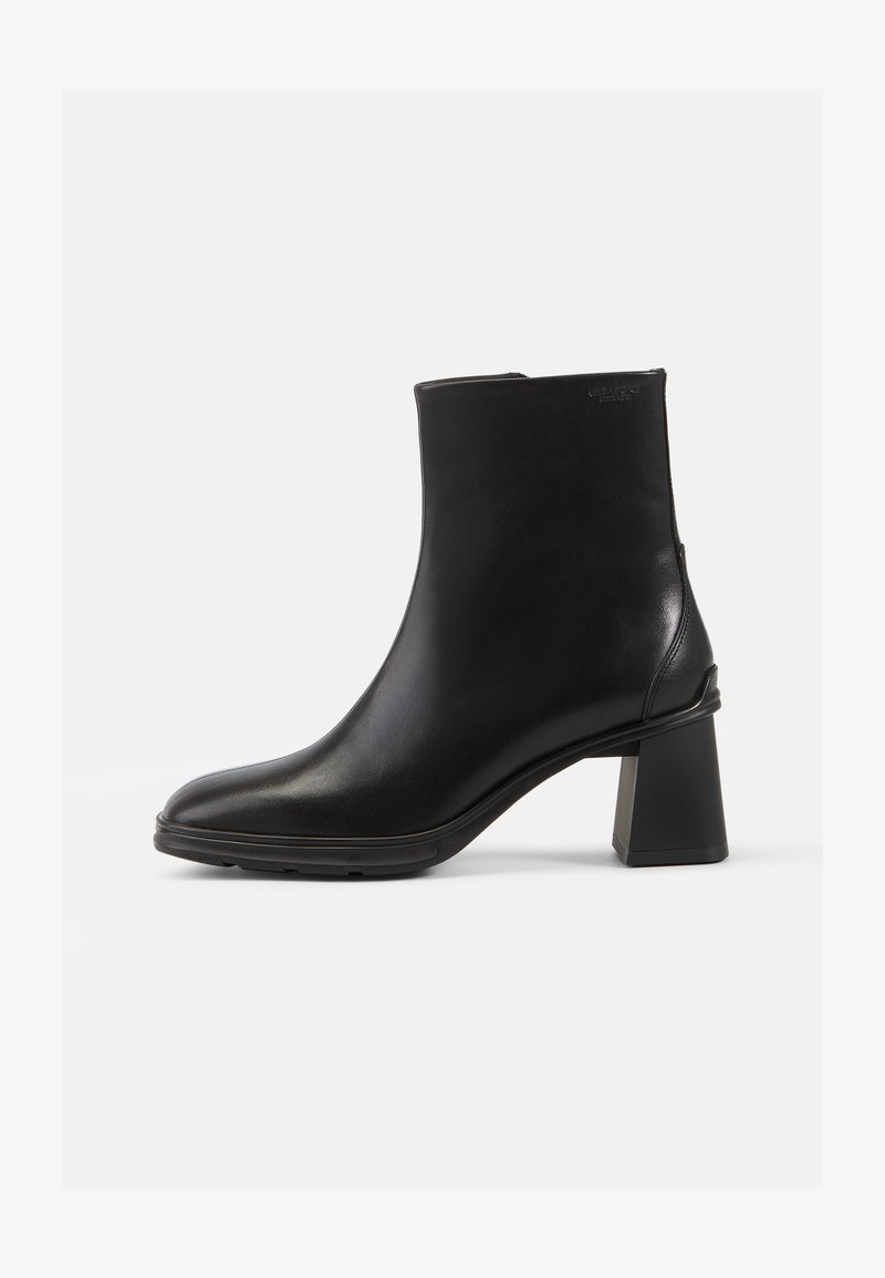 Bota de cuero negro hasta el tobillo con punta cuadrada y tacón cuadrado. Textura suave y diseño limpio, con un mínimo de adornos.