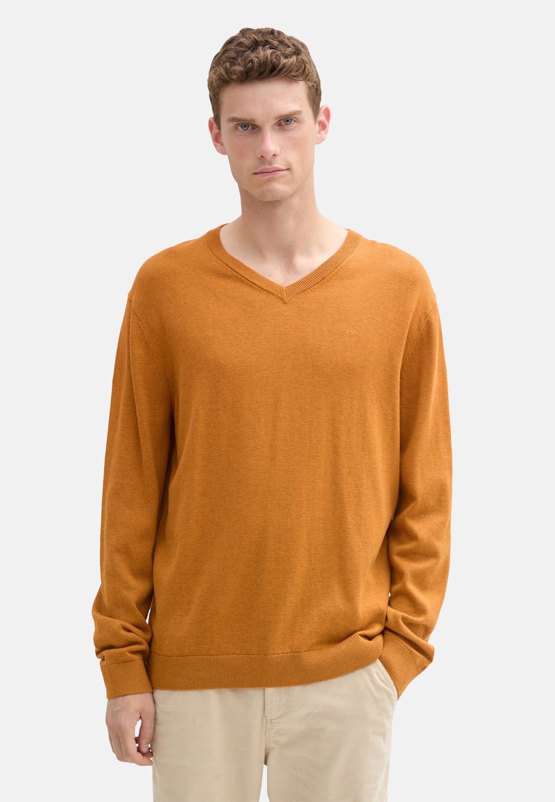 Suéter de cuello en V en un color naranja quemado, hecho de una tela suave. Presenta mangas largas y un dobladillo y puños acanalados. Diseño sencillo y clásico.