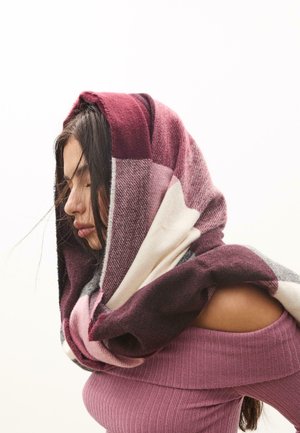 Écharpe à carreaux surdimensionnée dans des nuances de bordeaux, rose, gris et blanc. Texture douce avec des motifs variés, drapée élégamment autour des épaules.