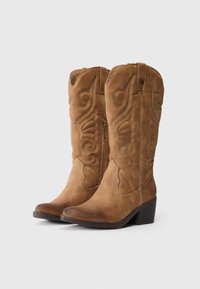 Ein Paar beige Wildleder-Cowboystiefel bis zur Mitte der Waden mit dekorativer Stickerei, seitlichem Reißverschluss und gestapelten Absätzen auf weißem Hintergrund.