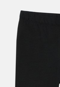Juodos legginsai, pagaminti iš lygaus, elastingo audinio, su elastinga juosmens juosta ir paprastu, be puošmenų dizainu.