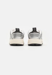 Srebrne buty sportowe z czarnymi akcentami, teksturowana siateczkowa cholewka, wyś cushioned kołnierz oraz solidna kremowa podeszwa. Tylny uchwyt ułatwiający zakładanie.