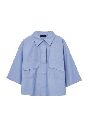 Chemise bleu clair à manches courtes avec un col et deux poches avant. Le tissu a une texture lisse et une coupe décontractée, surdimensionnée.