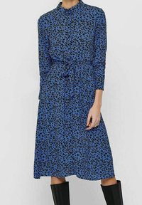 Abito blu con stampa leopardata, colletto, maniche lunghe, vita sottile e gonna fino al ginocchio. Tessuto morbido con dettagli neri.