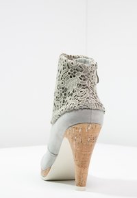Gray ankle boot with lace detailing, cork heel, and smooth upper material. Features a rounded toe and a zipper for closure.