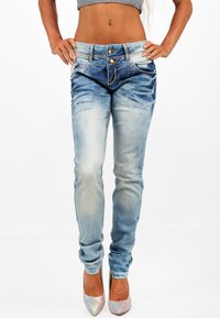 Jeans aderenti in denim blu sbiadito con vita alta, dotati di doppi bottoni, cuciture a contrasto e delicate sfumature di usura.