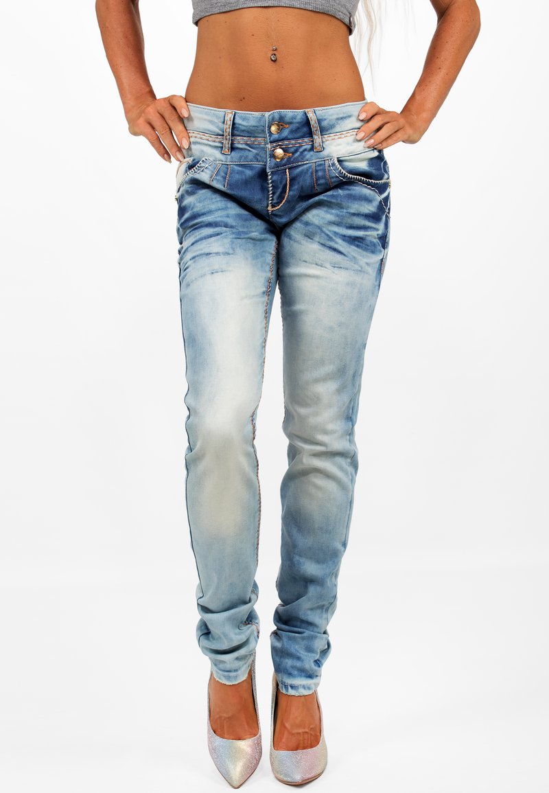 Jeans aderenti in denim blu sbiadito con vita alta, dotati di doppi bottoni, cuciture a contrasto e delicate sfumature di usura.