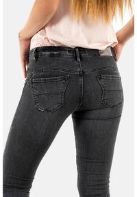 Svarta jeans i denim med en figurnära design, med hög midja, två bakfickor och subtila sömdetaljer. Slät textur och stretchigt material.