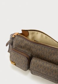 Bolsa-cinto castanha com monograma Michael Kors, com três compartimentos com fecho de correr, ferragens douradas e forro interior de tecido bege.