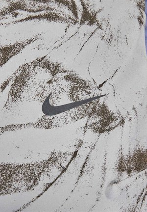 Nike Sportbekleidung mit einer strukturierten weißen Oberfläche, die mit braunen Farbspritzern versehen ist. Deutlich sichtbar ist das schwarze Nike-Logo.
