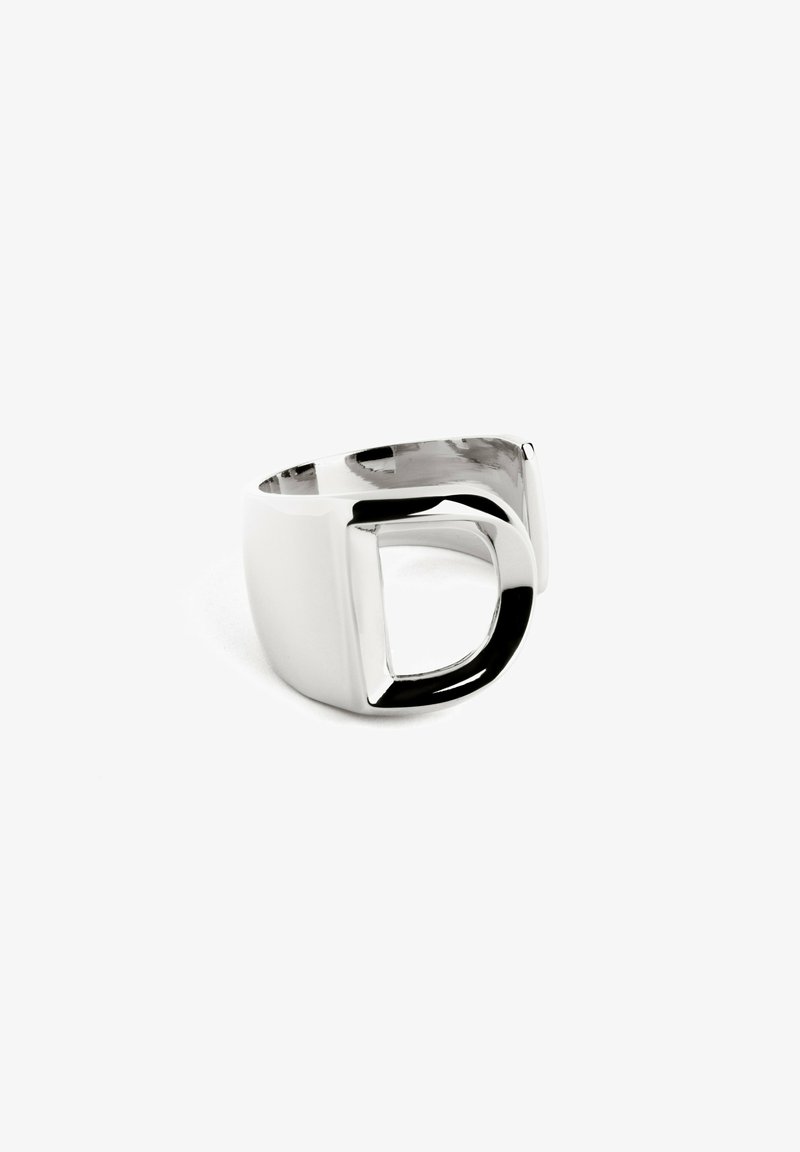 Anello in metallo argentato con un design ritagliato unico, finitura lucida e bordi arrotondati lisci, che unisce estetiche moderne e forme geometriche.