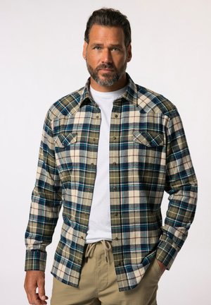 Camisa de franela a cuadros en verde, marino y crema con cuello abotonado, bolsillos en el pecho y mangas largas. Tela suave con una apariencia texturizada.