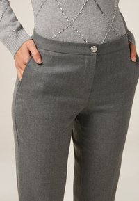 Szare spodni, elegancko skrojone, o gładkiej fakturze, z bocznymi kieszeniami i metalowym zapięciem na guzik w pasie dla dodatkowego akcentu.