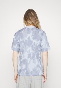 Short-sleeve t-shirt in light blue with a textured dot pattern. Features a round neckline and a relaxed fit with visible stitching detail.