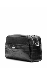 Czarna kosmetyczka ze skóry z tłoczeniem w kształcie krokodyla, o prostokątnym kształcie, z podwójnymi zamkami błyskawicznymi na górze oraz metalowym pierścieniem z boku do mocowania.