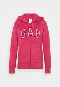 Felpa rosa con zip e cappuccio, tasche anteriori e logo "GAP" in grandi lettere sul petto.