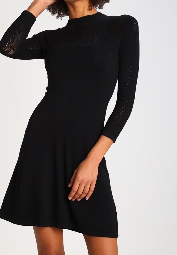 Robe en maille noire avec un corsage ajusté et une jupe évasée, dotée de manches longues avec un motif texturé le long des épaules et du haut des bras.