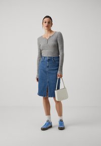 Grå ribbet langermet topp, denim midi skjørt med frontslitt, hvit skulderveske, blå joggesko og hvite sokker. Enkel design, uformell stil.