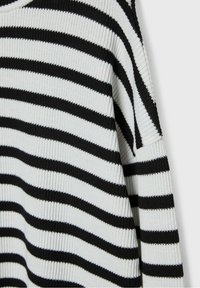 Pull en maille à rayures noires et blanches avec une coupe ample, présentant de larges rayures horizontales et une texture côtelée.