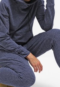 Survêtement à capuche bleu marine en tissu texturé avec un motif moucheté ; manches longues et coupe décontractée.